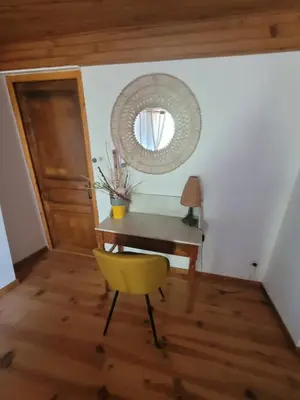 a table and a yellow chair in a room with a mirror at Gîte le Courdel in Les Brunels