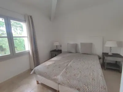 a white bedroom with a bed and two windows at La Redorte 17 in La Redorte