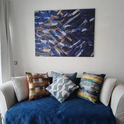 a blue couch with pillows sitting under a painting at La Redorte 17 in La Redorte