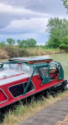 a red boat parked on the side of a river at Studio bateau au Somail in Saint-Nazaire-dʼAude