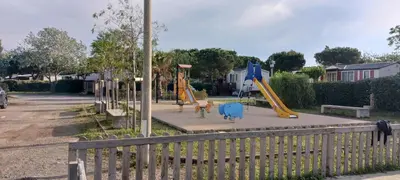 a park with a playground with slides and a fence at El sol in Port-la-Nouvelle