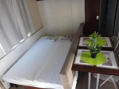 a small bed in a room with two tables at El sol in Port-la-Nouvelle