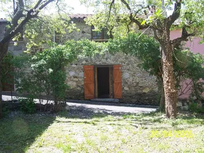 a stone building with a door and a tree at Vacances en pays cathare réservable du samedi au samedi les mois de Juillet et Aout in Joucou