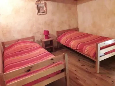 two twin beds in a room with wooden floors at Vacances en pays cathare réservable du samedi au samedi les mois de Juillet et Aout in Joucou