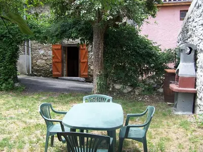 a table and chairs in a yard with a tree at Vacances en pays cathare réservable du samedi au samedi les mois de Juillet et Aout in Joucou