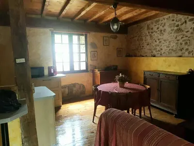a room with a table and a kitchen with a window at Vacances en pays cathare réservable du samedi au samedi les mois de Juillet et Aout in Joucou