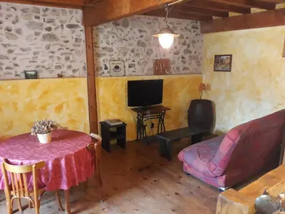 a living room with a table and a couch and a tv at Vacances en pays cathare réservable du samedi au samedi les mois de Juillet et Aout in Joucou