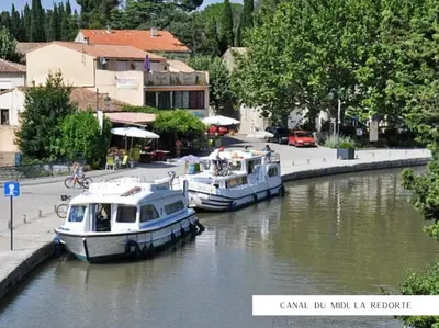 two boats docked in a canal in a city at Bienvenue chez Sandrine in La Redorte