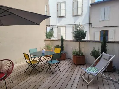 a patio with a table and chairs on a deck at Le Baron terrasse et parking cœur de Castres in Castres