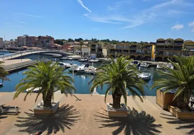 a group of palm trees in a marina with boats at Ciel & Sel in Gruissan