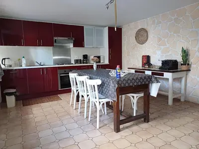 a kitchen with a table with white chairs and red cabinets at Sidobre in Lacrouzette