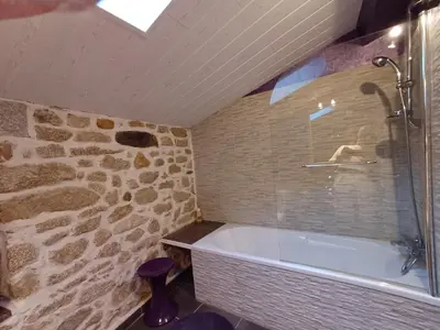 a bathroom with a tub and a stone wall at Sidobre in Lacrouzette