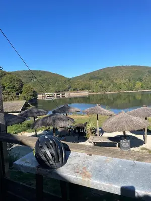 a group of tables with umbrellas next to a lake at Large charming house surrounded by nature in Brassac