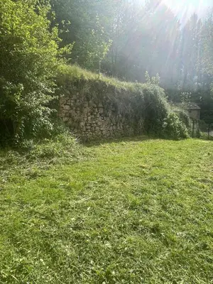 a stone wall in a field with green grass at Large charming house surrounded by nature in Brassac