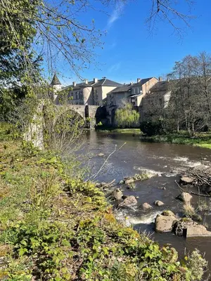 a river with a bridge and buildings in the background at Large charming house surrounded by nature in Brassac