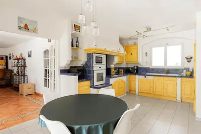 a kitchen with a black table and yellow cabinets at Villa La Cavayere swimming pool air conditioning in Carcassonne
