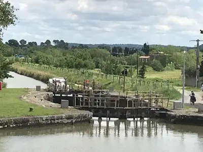 a bridge over a river next to a field at La maison Pont Rouge in Carcassonne