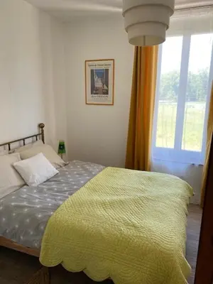 a bedroom with a bed with a yellow blanket and a window at La maison Pont Rouge in Carcassonne