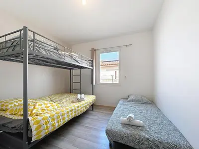 a bedroom with two bunk beds and a window at Villa Grivia - Maison avec grand jardin - Piscine - Pétanque - Ping Pong in Saint-André-de-Roquelongue