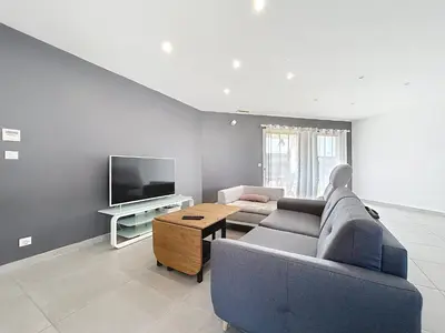 a living room with a blue couch and a tv at Villa Grivia - Maison avec grand jardin - Piscine - Pétanque - Ping Pong in Saint-André-de-Roquelongue