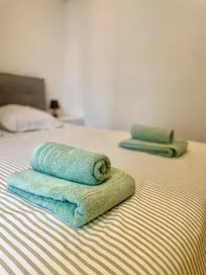 a stack of towels sitting on top of a bed at T3 Lumineux & Cosy avec Balcon Escapade by DarBonne in Narbonne