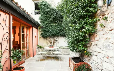 a patio with a table and chairs next to a building at Charming Riverside House In Medieval Village in Villeneuve-Minervois