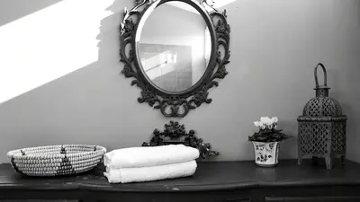 a mirror on a wall above a table with towels at Charming Riverside House In Medieval Village in Villeneuve-Minervois