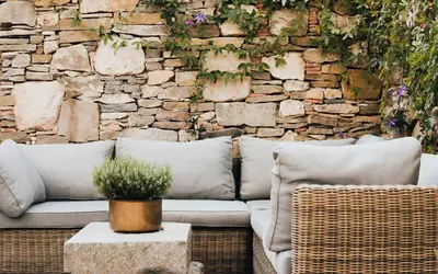 a living room with a couch and a stone wall at Charming Riverside House In Medieval Village in Villeneuve-Minervois