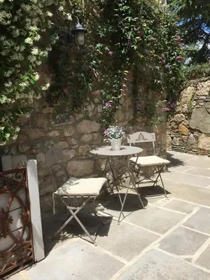 a table and two chairs in front of a stone wall at Charming Riverside House In Medieval Village in Villeneuve-Minervois