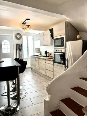 a kitchen with a refrigerator and a table in it at Gîte Molière in Sallèles-dʼAude