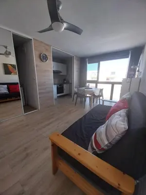 a bedroom with a bed and a living room with a table at Appartement T2 lumineux à 200m de la plage, tout équipé in Port-la-Nouvelle