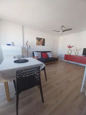 a living room with a table and a couch at Appartement T2 lumineux à 200m de la plage, tout équipé in Port-la-Nouvelle