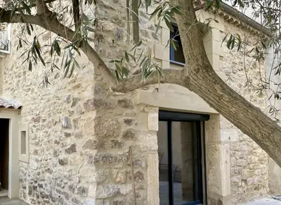 a stone building with a tree next to a door at Le Mas de l'eau - Piscine Privative in Quarante