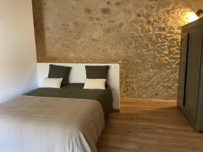 a bedroom with a bed and a stone wall at Le Mas de l'eau - Piscine Privative in Quarante
