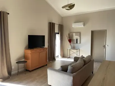a living room with a couch and a flat screen tv at Le Mas de l'eau - Piscine Privative in Quarante