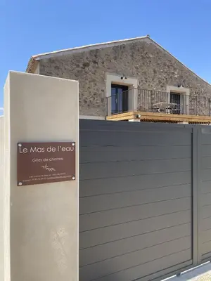 a garage door with a sign on it in front of a building at Le Mas de l'eau - Piscine Privative in Quarante