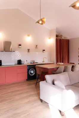 a kitchen and living room with red cabinets at Le Mas de l'eau - Piscine Privative in Quarante