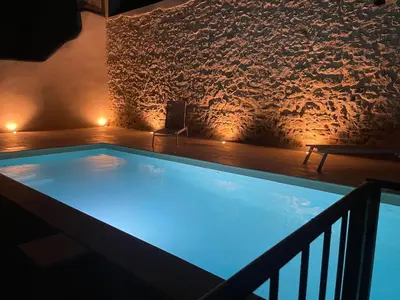 a swimming pool in a room with a brick wall at Le Mas de l'eau - Piscine Privative in Quarante