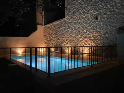 a swimming pool at night next to a wall at Le Mas de l'eau - Piscine Privative in Quarante