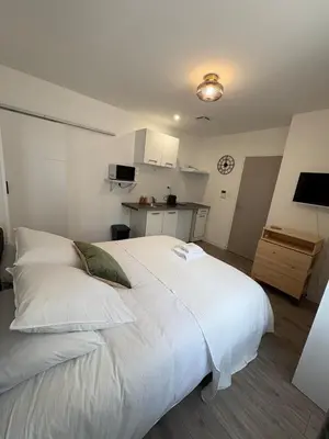 a large white bed in a room with a kitchen at Studio in Mirepoix