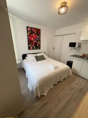 a bedroom with a white bed and a painting on the wall at Studio in Mirepoix