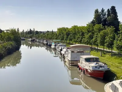 a row of boats docked in a river at La Villa les Terrasses du Canal in Capestang