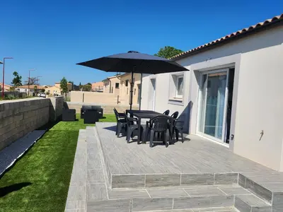 a patio with a table and chairs and an umbrella at La Villa les Terrasses du Canal in Capestang