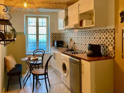 a kitchen with a washing machine and a table at Le Repaire Légendaire in Carcassonne