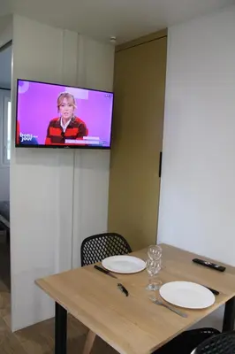 a television on a wall above a table with chairs at Studiotel premium 2 personnes in Pamiers