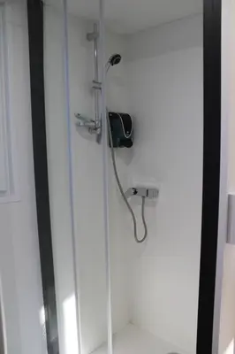 a shower with a hose attached to a wall at Studiotel premium 2 personnes in Pamiers