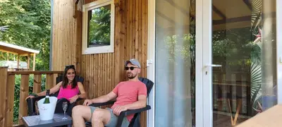 a man and woman sitting on the porch of a cabin at Studiotel premium 2 personnes in Pamiers