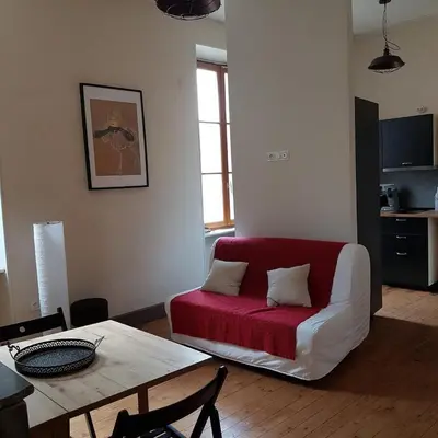 a living room with a red couch and a table at Gîte de la tour avec piscine entre Carcassonne et narbonne in Capendu