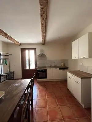 a kitchen with white cabinets and a wooden table at Gîte de Montplo-Cruzy in Cruzy