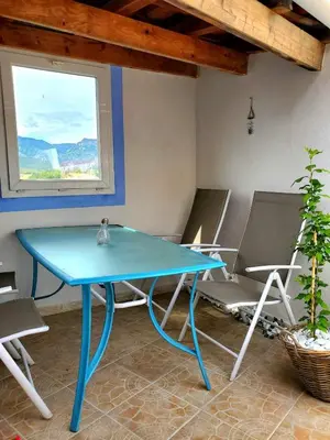 a blue table and chairs in a room with a window at Renovated and air-conditioned 2-bedroom apartment with terrace in Saint-Paul-de-Fenouillet